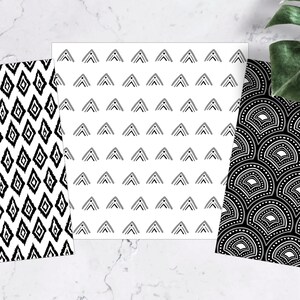 Pu&ograve; includere: Tre carte decorate con disegni in bianco e nero. Una ha un motivo ikat a diamante, un'altra presenta file di triangoli e la terza ha un motivo a ventaglio. Una foglia verde &egrave; sullo sfondo.