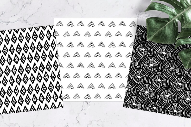 Pu&ograve; includere: Tre carte decorate con disegni in bianco e nero. Una ha un motivo ikat a diamante, un'altra presenta file di triangoli e la terza ha un motivo a ventaglio. Una foglia verde &egrave; sullo sfondo.