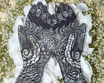 May include: A pair of black paper cut hands with intricate designs, resembling henna, against a background of white flower petals.