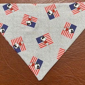 May include: A gray bandana with a repeating pattern of a cartoon dog wearing sunglasses and a red shirt standing in front of an American flag.