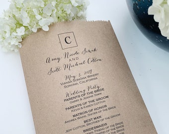 May include: A brown paper wedding program with black text. The program lists the names of the bride and groom, the date, location, and the wedding party. White flowers are in the background.
