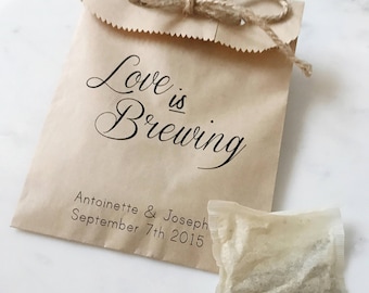 May include: A small brown paper bag with the text "Love is Brewing" and the names Antoinette & Joseph, September 7th 2015. The bag is tied with twine and has a tea bag next to it. Wedding favor.