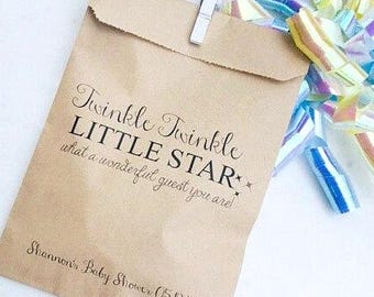 May include: A kraft paper gift bag with the text "Twinkle Twinkle LITTLE STAR what a wonderful guest you are!" and "Shannon's Baby Shower 05DD". The bag is clipped shut with a white clothespin and has a colorful bow.