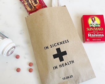 May include: A brown paper bag with the text "In Sickness + In Health" and the date "10.28.22". The bag contains a chocolate chip cookie, a small white packet, and a box of Sun-Maid raisins.