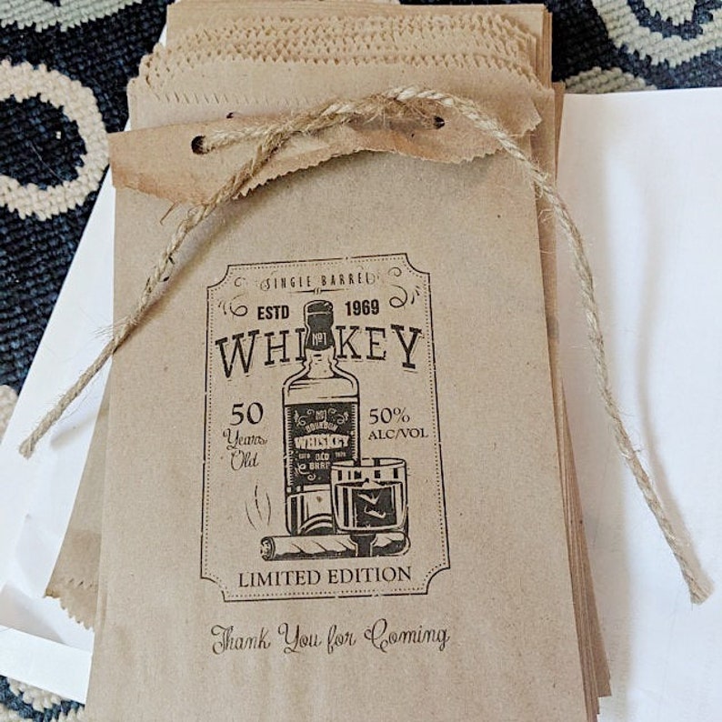Puede incluir: Bolsas de papel marr&oacute;n con un dise&ntilde;o de etiqueta de whisky vintage. La etiqueta presenta una botella de whisky, un vaso y un cigarro. El texto de la etiqueta dice "Single Barred, Est. 1969, Whiskey, 50 Years Old, 50% Alc/Vol, Limited Edition, Thank You for Coming."