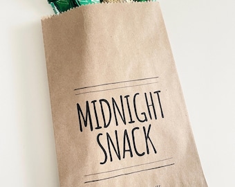 May include: A brown paper bag filled with green and gold wrapped candies. The bag has the words "MIDNIGHT SNACK" printed on it in black, with "LOVE MICKEY & MINNIE" printed below.