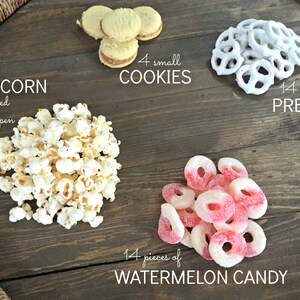 Puede incluir: Una bandeja de madera con una variedad de aperitivos, incluyendo palomitas de ma&iacute;z, galletas, pretzels y caramelos de sand&iacute;a. La bandeja est&aacute; decorada con un borde de cuerda trenzada. El texto en la bandeja dice: "POPCORN 1 cup closed 2 cups open", "4 small COOKIES", "14 chocolate PRETZELS", y "14 pieces of WATERMELON CANDY".