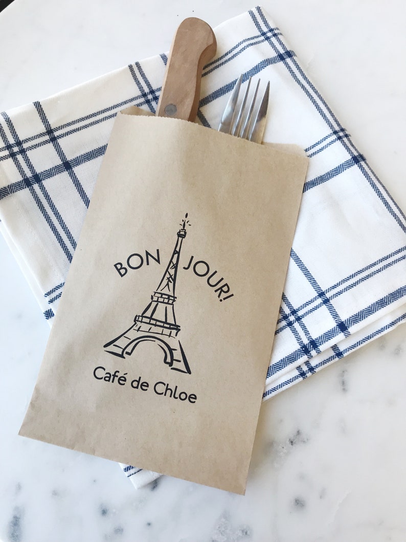 May include: A brown paper bag with a black and white illustration of the Eiffel Tower and the text "Bon Jour! Cafe de Chloe" printed on it.
