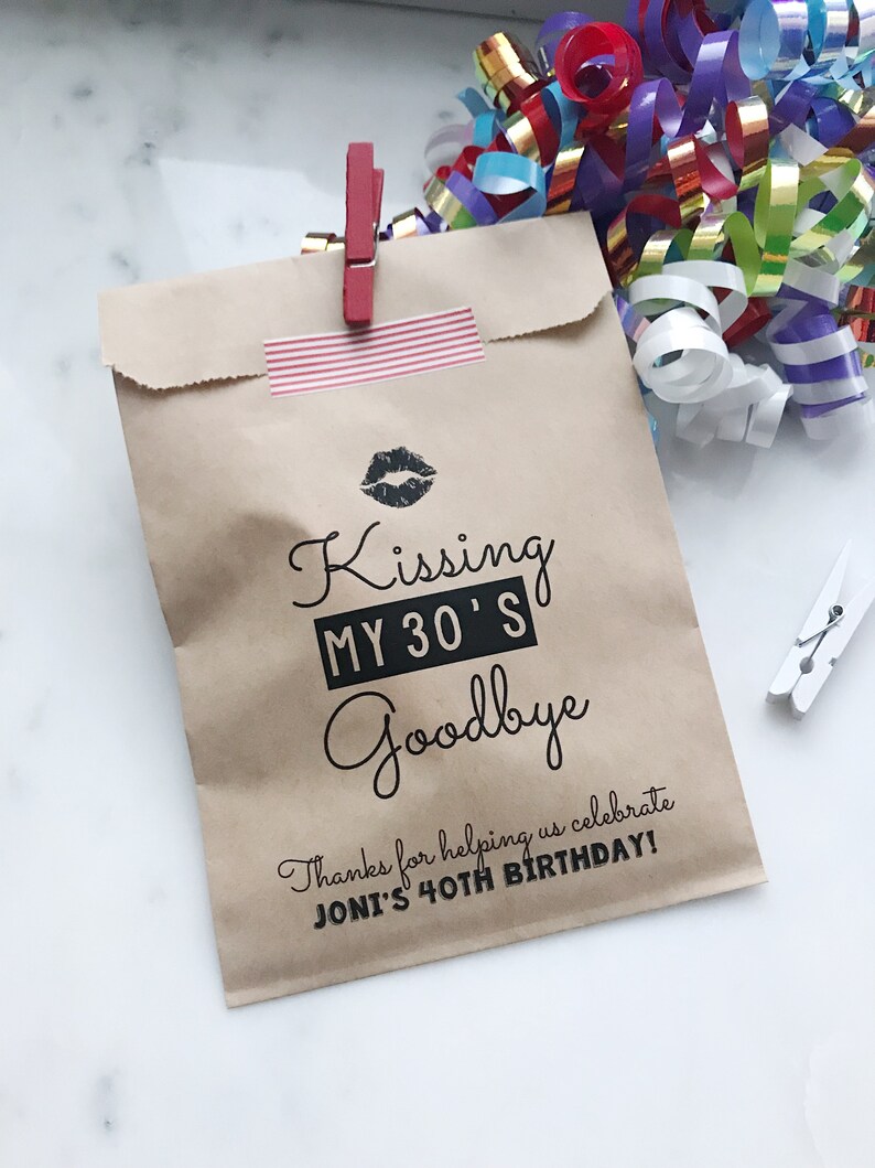 Puede incluir: Bolsa de papel marr&oacute;n con una pegatina a rayas rojas y blancas y un gr&aacute;fico en blanco y negro que dice "Kissing My 30's Goodbye" y "&iexcl;Gracias por ayudarnos a celebrar el 40 cumplea&ntilde;os de Joni!"