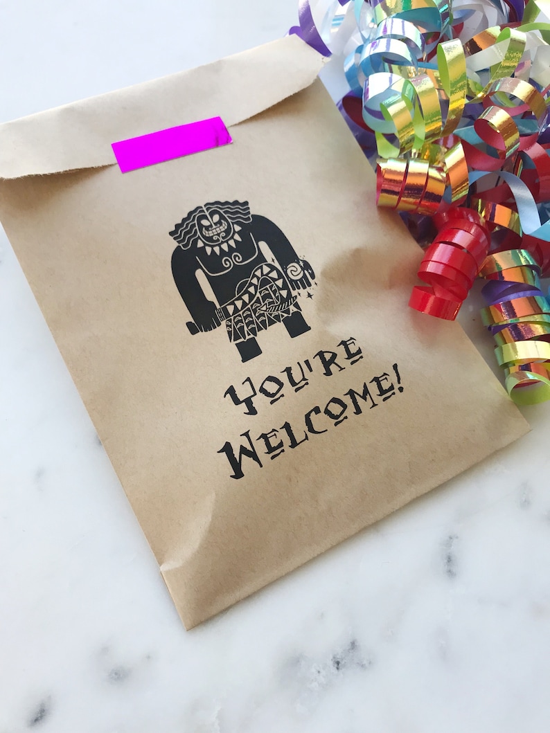 May include: A brown paper bag with a black and white illustration of a cartoon character. The bag has a pink piece of tape on the top and the text "You're Welcome!" printed on the front.