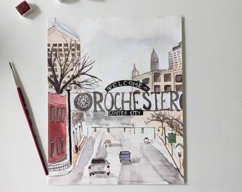 Peut inclure: Peinture à l'aquarelle de Rochester, Center City, avec une scène de rue avec des voitures et des bâtiments. L'œuvre comprend le texte "WELCOME ROCHESTER CENTER CITY". Une règle et du matériel de peinture sont également visibles.