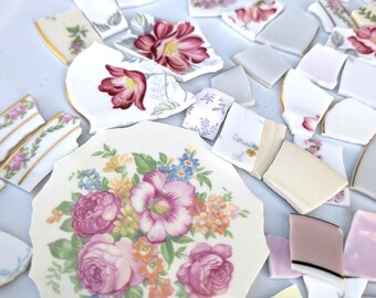 Peut inclure: Fragments de porcelaine cassée éparpillés, ornés de motifs floraux roses, rouges, jaunes et bleus. Certains morceaux présentent des bordures dorées. Les éclats, de tailles et formes variées, sont idéaux pour le mosaïque ou le bricolage.