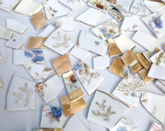 Peut inclure: Fragments de céramique cassée avec des motifs floraux et dorés. Les morceaux, de tailles et formes variées, présentent des fonds blancs ornés de motifs bleus, rouges et dorés. Idéal pour l'art de la mosaïque ou les projets artisanaux.