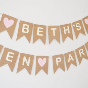 May include: A brown paper banner with the text "Beth's Hen Party" in white letters. The banner has pink hearts between the words.
