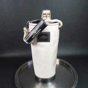 May include: White canvas champagne bottle carrier with black leather trim and a rope handle. The carrier has the text "Moët & Chandon" printed on it.