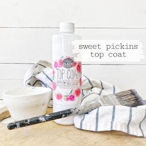 May include: A clear bottle of Sweet Pickins Top Coat flat matte finish wood, furniture, and craft paint. The bottle is labeled with a floral design and the text "Sweet Pickins Top Coat".