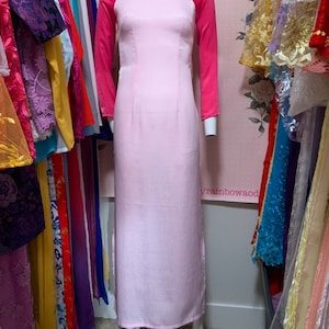 May include: A pink and red long-sleeved dress with a mandarin collar. The dress has a fitted bodice and a flowing skirt. The sleeves are a contrasting red color.