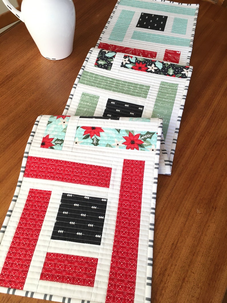 K&ouml;nnte beinhalten: Ein Set aus vier gesteppten Tischl&auml;ufern im Weihnachtsdesign. Die L&auml;ufer haben ein geometrisches Muster in Rot und Wei&szlig; mit schwarzen Akzenten. Der Stoff hat einen festlichen Weihnachtsdruck mit Weihnachtssternen und Stechpalmen.