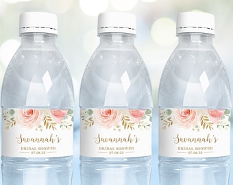 May include: Three clear plastic water bottles with white caps. Each bottle has a label with the text "Savannah's Bridal Shower 07.08.23". The labels feature a floral design with pink roses, gold accents, and green leaves.