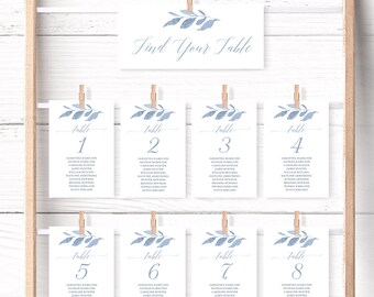 Puede incluir: Tarjetas de número de mesa de boda azul y blanco con un diseño de hoja de acuarela. Las tarjetas están numeradas del 1 al 8 e incluyen una lista de nombres de invitados. Las tarjetas se muestran en un fondo de madera blanco con las palabras "Find Your Table" en la parte superior.