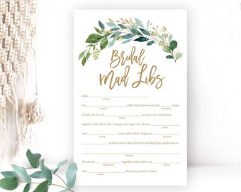Op de afbeelding: Een printbare bruidsdouche-spelkaart met een groene bladrand en gouden tekst die "Bridal Mad Libs" luidt. De kaart bevat zinnen met lege plekken die gasten kunnen invullen.