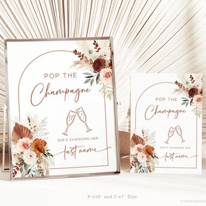 Könnte beinhalten: Zwei druckbare Schilder im Boho-Stil. Die Schilder zeigen den Text "Pop the Champagne" und "She's changing her last name". Die Schilder sind 20,32 cm x 25,4 cm und 12,7 cm x 17,78 cm groß.