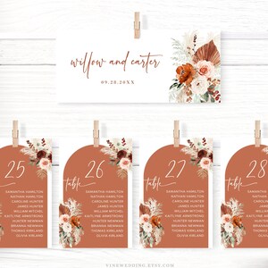 Puede incluir: Un conjunto de cuatro tarjetas de n&uacute;mero de mesa con un tema boho. Las tarjetas son marrones con un arco redondeado en la parte superior. Cada tarjeta tiene un arreglo floral con hierbas secas y hierba de la pampa. Los n&uacute;meros de mesa son 25, 26, 27 y 28. Cada tarjeta tambi&eacute;n tiene una lista de nombres para los invitados de cada mesa.