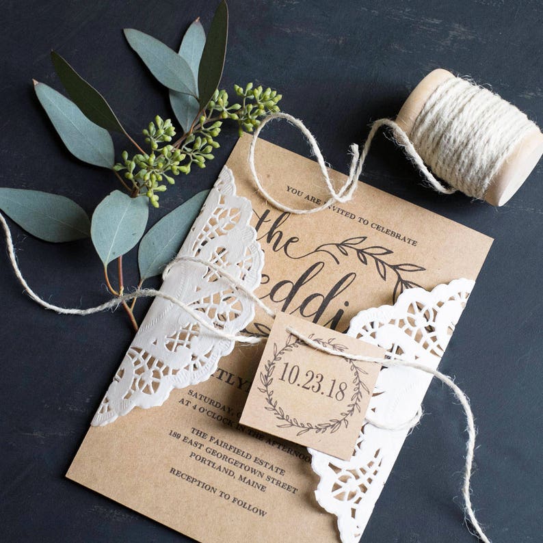 K&ouml;nnte beinhalten: Eine rustikale Hochzeitseinladung mit braunem Papierhintergrund und wei&szlig;er Spitzen&uuml;berlagerung. Die Einladung enth&auml;lt den Text "Sie sind eingeladen, die Hochzeit zu feiern" und das Datum "10.23.18".