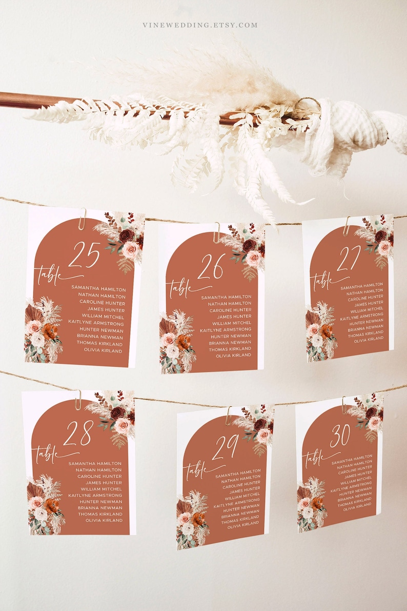 Puede incluir: Conjunto de seis tarjetas de n&uacute;mero de mesa con fondo terracota e ilustraciones florales. Los n&uacute;meros son 25, 26, 27, 28, 29 y 30. Cada tarjeta tiene una lista de nombres debajo del n&uacute;mero.