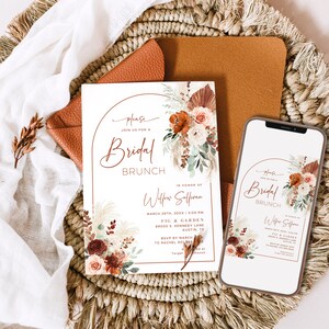 May include: A white invitation card with a brown arch and floral design. The text on the card reads "Please join us for a Bridal Brunch in honor of Willow Soffion. March 28th, 20XX | 3:00 PM. Fig & Garden, 89000 S. Kennedy Lane, Austin, TX. RSVP by March to Rachel 001880. Target"