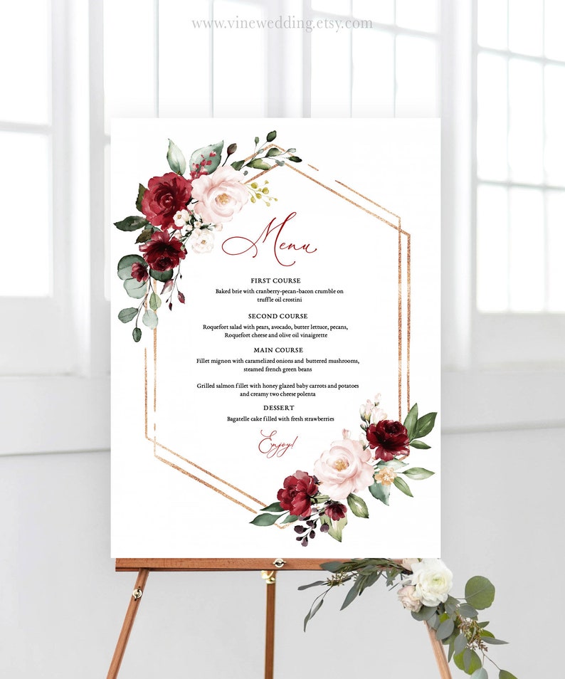 Peut inclure: Un menu de mariage avec un cadre g&eacute;om&eacute;trique dor&eacute; et des accents floraux. Le menu liste les plats : Premier plat, Deuxi&egrave;me plat, Plat principal et Dessert. Le texte "Menu" est &eacute;crit en cursive.