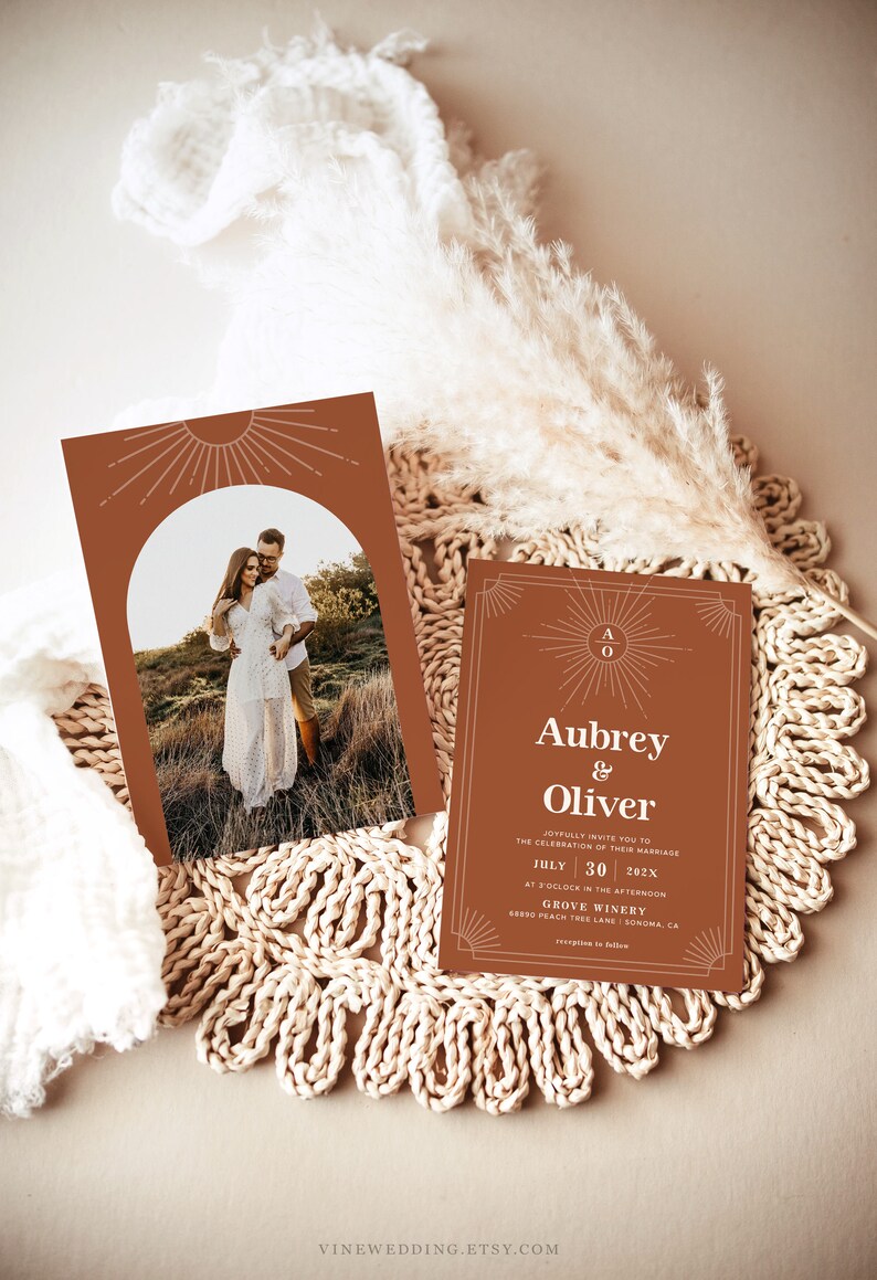Peut inclure: Deux faire-part de mariage couleur terre cuite avec un motif de soleil. L'un pr&eacute;sente une photo d'un couple, l'autre porte les noms "Aubrey & Oliver" et les d&eacute;tails du mariage. Les invitations sont sur un dessous de plat tiss&eacute;.