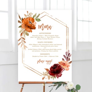 May include: A wedding menu sign with a gold geometric frame and floral accents in shades of orange, red, and gold. The menu lists appetizers, main courses, and desserts. The text reads "Menu", "Appetizers", "Main Courses", "Desserts", and "Please enjoy!"