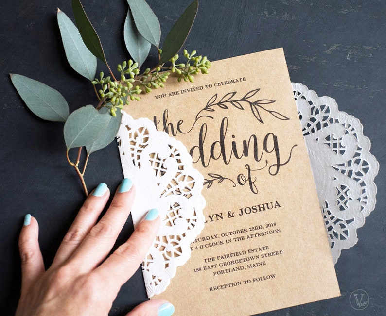 K&ouml;nnte beinhalten: Eine braune Papier-Hochzeitseinladung mit wei&szlig;er Spitzen&uuml;berlagerung. Die Einladung lautet "Sie sind eingeladen, die Hochzeit von Lynn & Joshua zu feiern" und enth&auml;lt Datum, Uhrzeit und Ort der Hochzeit.