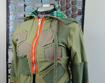 May include: A green hooded jacket with orange stitching and a zipper. The jacket has a geometric design with multiple panels and pockets.
