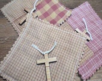 May include: Four small fabric pouches with a cross charm attached to each. The pouches are made of a red and tan plaid fabric and a tan and brown plaid fabric.