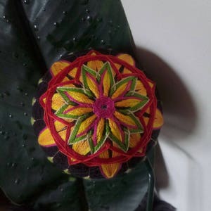 May include: A colorful, hand-stitched Japanese decorative ball, known as a "Temari", with a red, yellow, green, and pink floral design.
