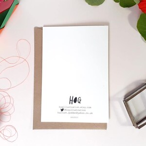 May include: A white card with brown paper backing. The card has black text that reads "HOG" and includes contact information for the artist. The text reads "hogillustration.etsy.com", "@hogillustration", and "harriet_godden@yahoo.co.uk".