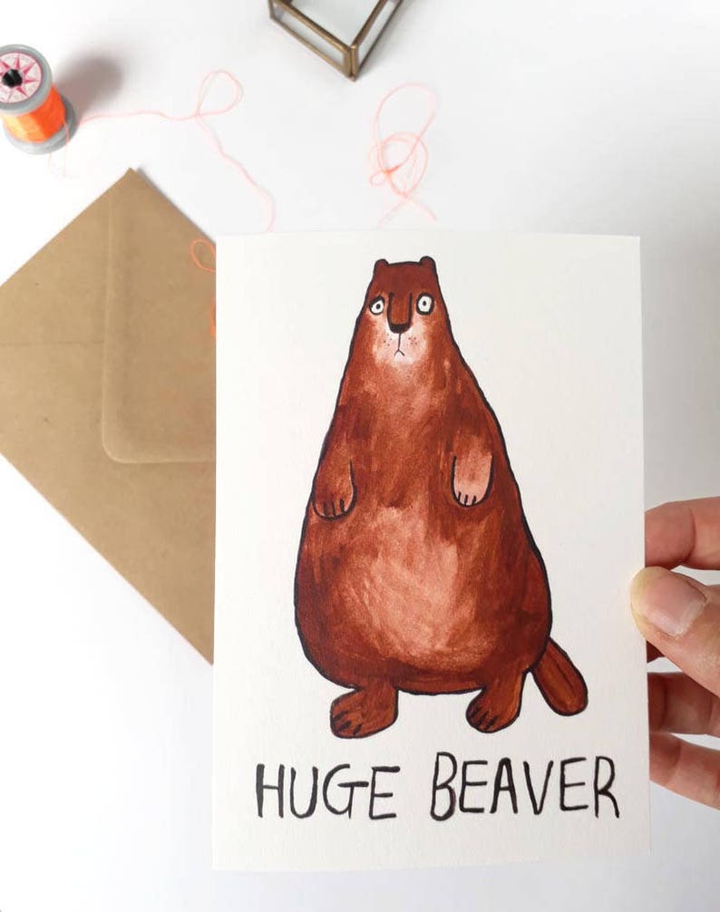 May include: A greeting card with a cartoon illustration of a brown beaver. The beaver is standing on its hind legs with its paws in the air. The text "HUGE BEAVER" is written below the beaver.