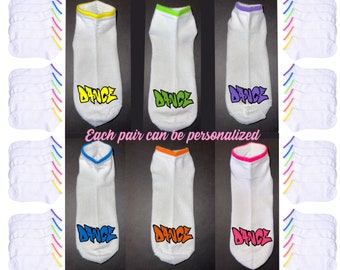 May include: A set of 12 white ankle socks with neon colored trim. Each sock has the word "DANCE" written on it in a graffiti style font. The socks are arranged in three rows of four. Each pair can be personalized.