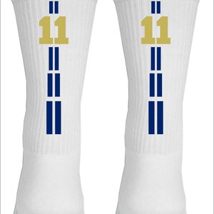 May include: A pair of white athletic socks with blue stripes and a gold number 11 on each sock.