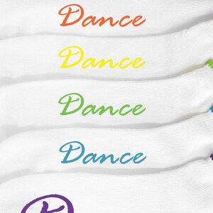 May include: Six white socks with the word "Dance" written on them in different colors: red, orange, yellow, green, blue, and purple.