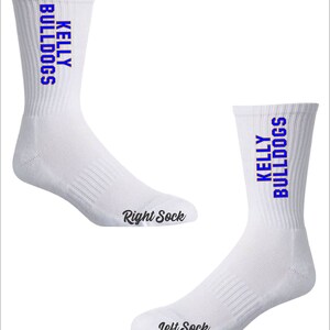May include: A pair of white crew socks with blue and orange text that reads "KELLY BULLDOGS". The socks are labeled "Right Sock" and "Left Sock".