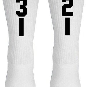 May include: A pair of white crew socks with black numbers, one sock has the number "31" and the other sock has the number "21".