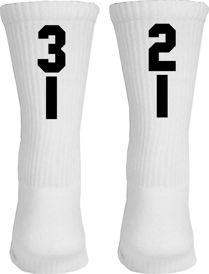 May include: A pair of white crew socks with black numbers, one sock has the number "31" and the other sock has the number "21".