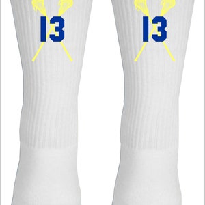 May include: A pair of white athletic socks with a yellow lacrosse stick design and the number 13 in blue.