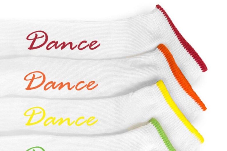 May include: Four pairs of white socks with colorful trim. Each sock has the word "Dance" written on it in a different color: red, orange, yellow, and green.