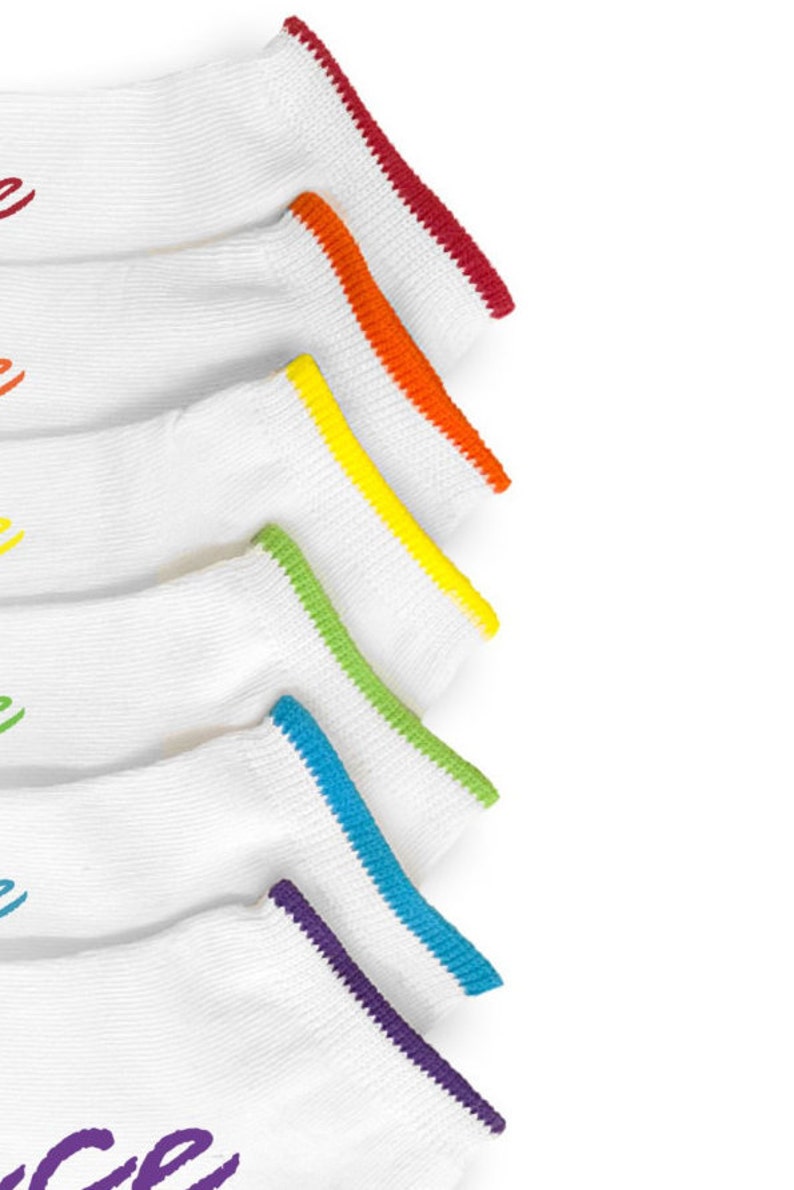 May include: Five pairs of white ankle socks with colorful trim. The trim colors are red, orange, yellow, green, and purple.