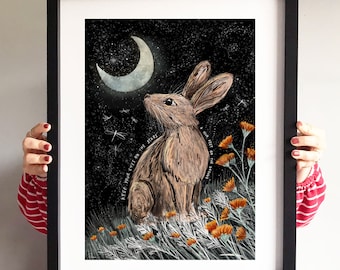 May include: A framed illustration of a brown rabbit sitting in a field of orange flowers under a crescent moon and a starry night sky. The text "Keep your eyes on the stars and your feet on the ground" is written in a cursive font.