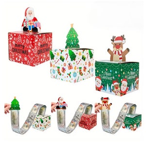 May include: Christmas-themed gift boxes with pop-up characters, including Santa, a Christmas tree, and a reindeer. The boxes feature festive patterns and the text "Merry Christmas." Each box is designed to dispense money.